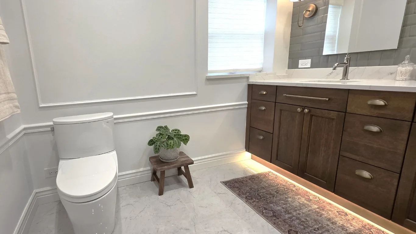 Modern bathroom renovation in Chicago featuring white subway tile walls, veined floor tiles, and gold hardware.